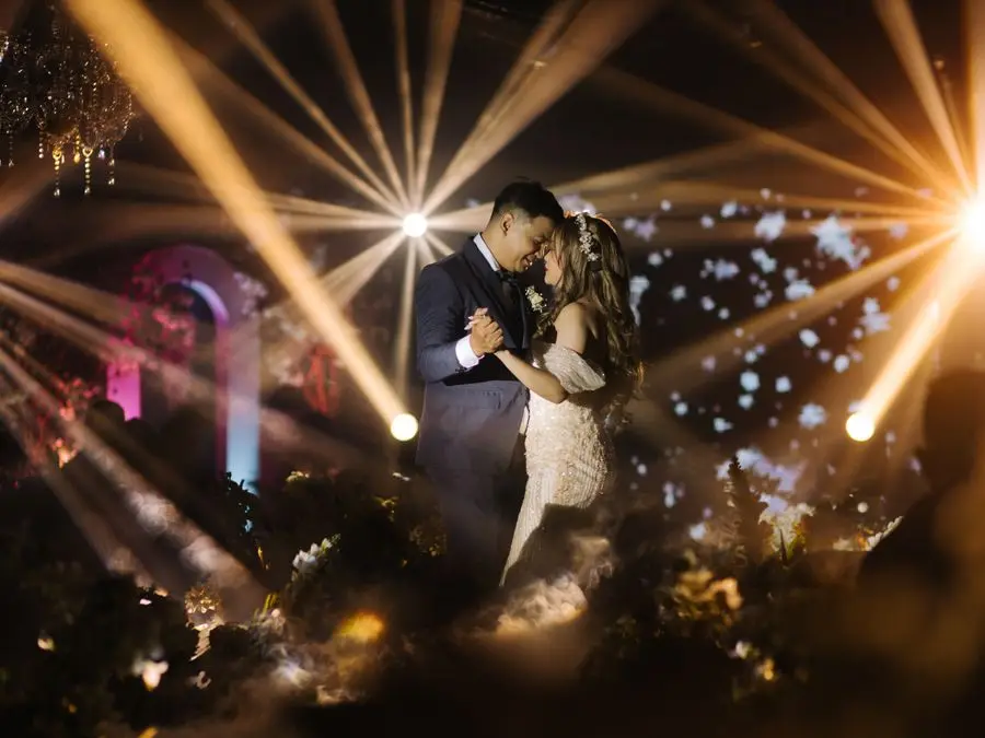 Casal de noivos dançando sob spots de luz em uma festa de casamento