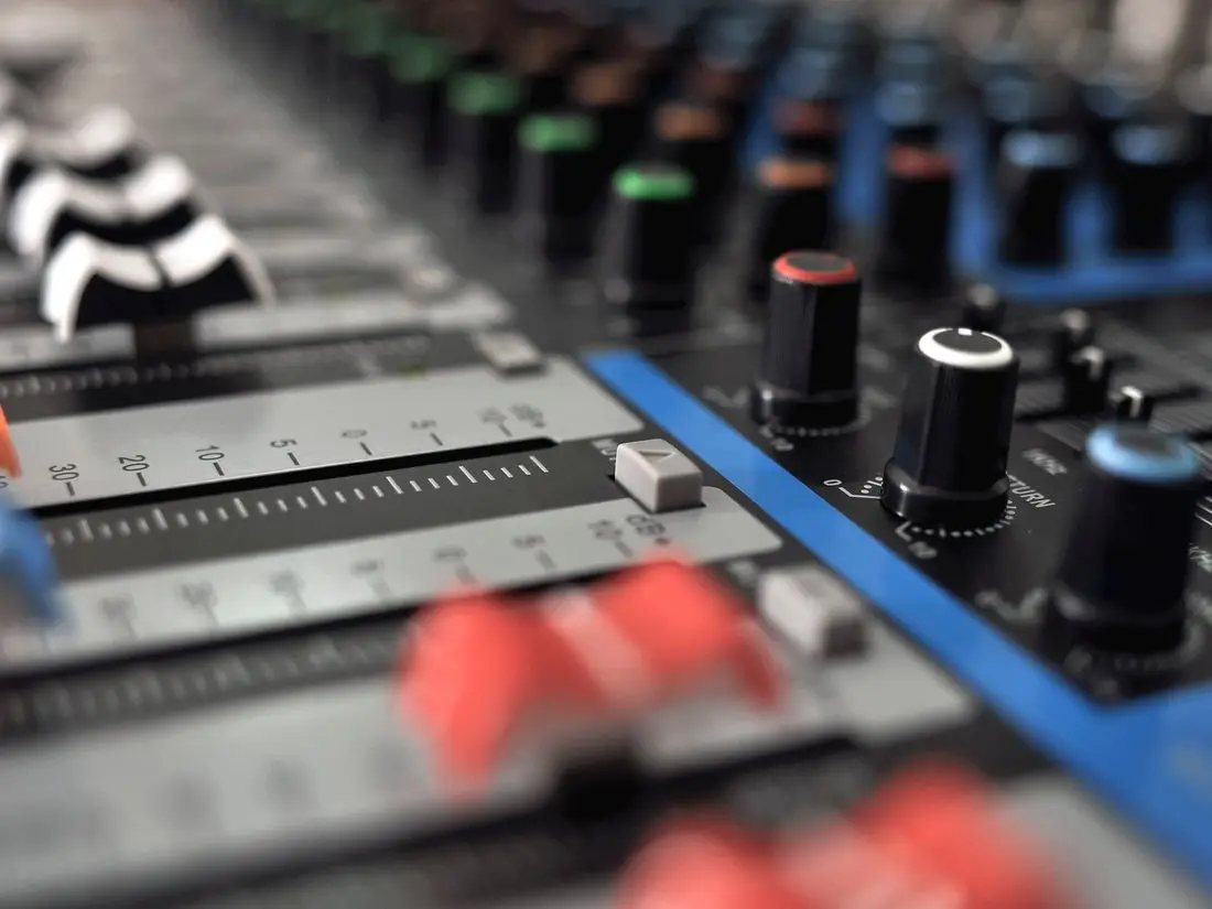 Mesa de som digital com faders e controles iluminados durante a operação de um evento