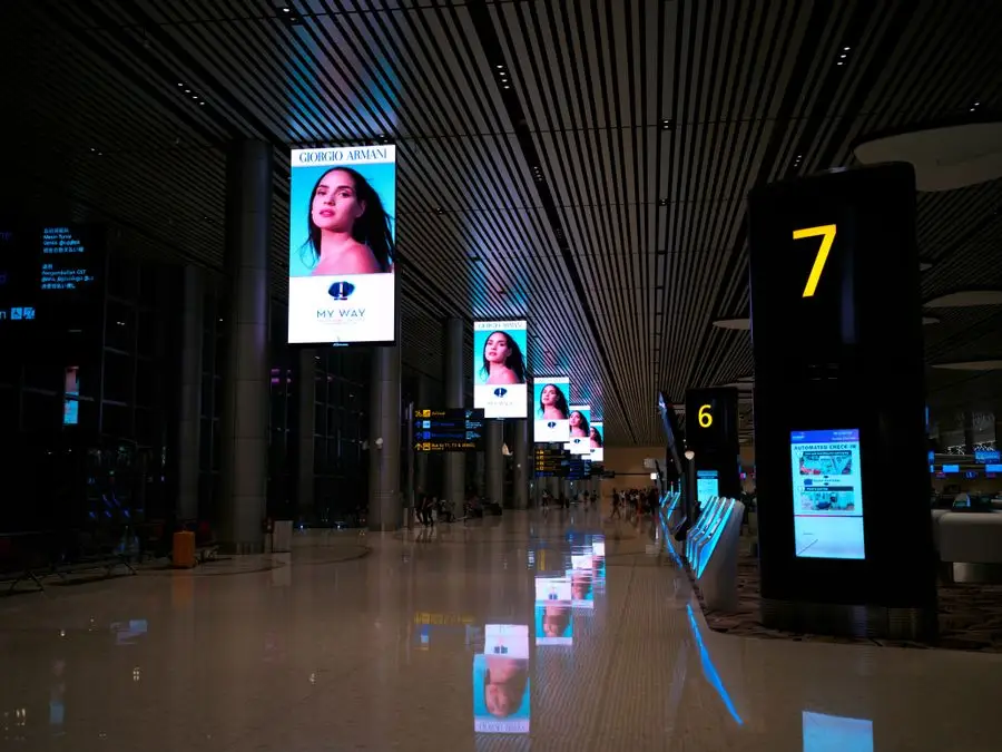Totens e telas digitais verticais iluminando uma área de circulação